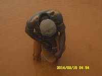 Miner panning for gold with traditional wooden bowl in Ghana