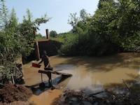 Person processing soil on the river Okame